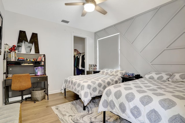 bedroom with hardwood / wood-style flooring, a spacious closet, a closet, and ceiling fan