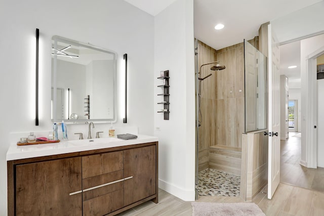 bathroom with vanity, wood-type flooring, and tiled shower