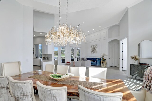 dining space featuring french doors, a chandelier, a high ceiling, and sink