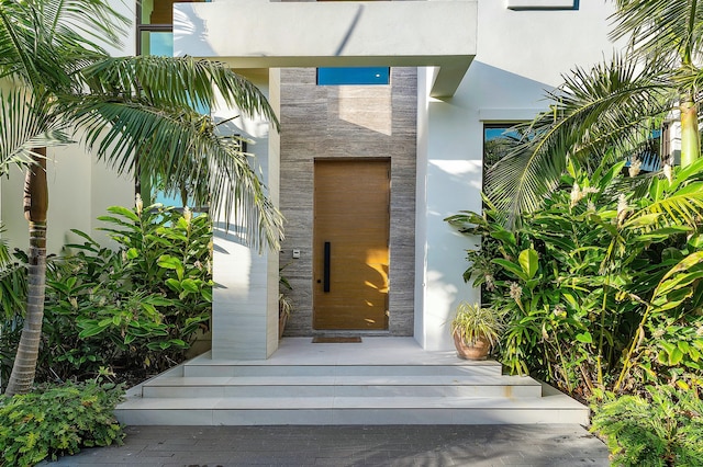 doorway to property featuring stone siding and stucco siding