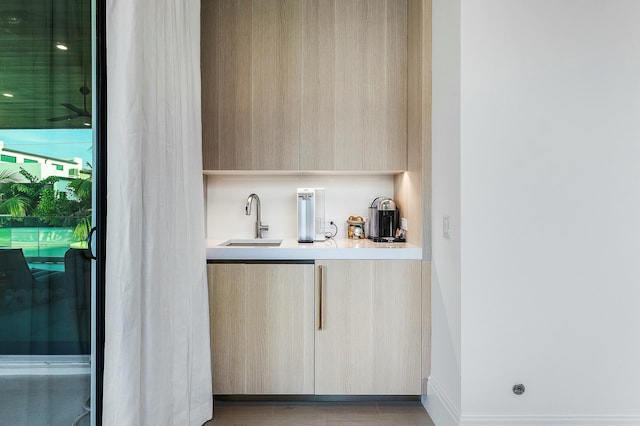 bar featuring light brown cabinetry and sink