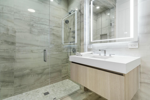 bathroom featuring vanity, a shower with shower door, and tasteful backsplash