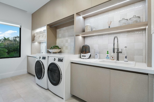 washroom with cabinets, light tile patterned floors, washing machine and dryer, and sink