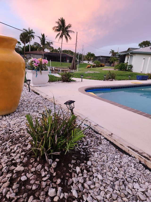 pool at dusk with a lawn and a patio area