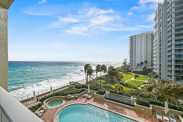 view of swimming pool with a water view and a view of the beach