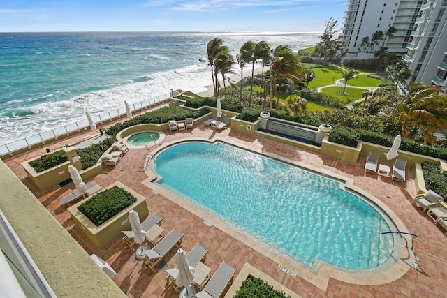 view of swimming pool with a water view and a beach view