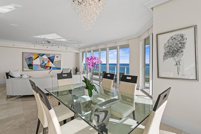 dining space with track lighting, floor to ceiling windows, ornamental molding, a water view, and an inviting chandelier