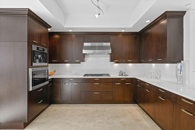 kitchen featuring black microwave, stainless steel gas cooktop, extractor fan, track lighting, and dark brown cabinets