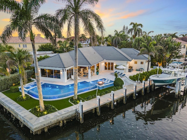 back house at dusk featuring a patio area and a water view