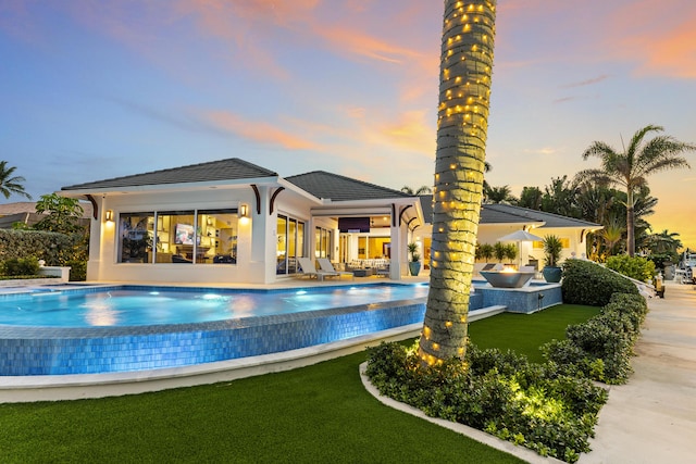 pool at dusk with outdoor lounge area and a patio area