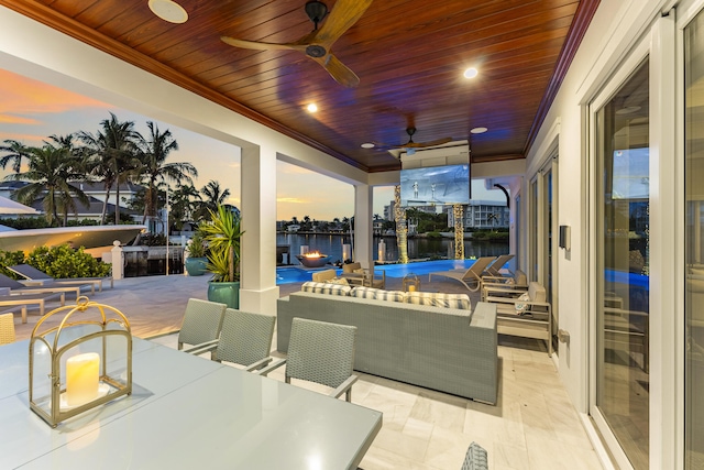 patio terrace at dusk featuring ceiling fan, a water view, and a pool