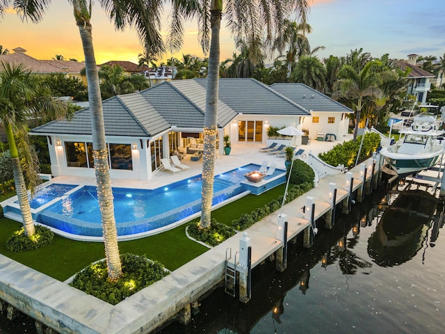 back house at dusk featuring pool water feature and a patio