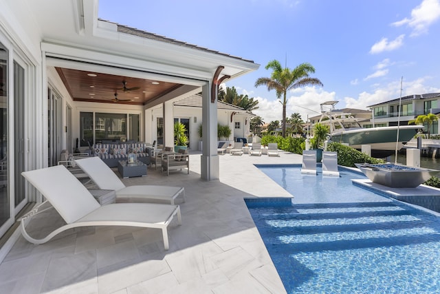 view of pool with an outdoor living space, ceiling fan, and a patio area