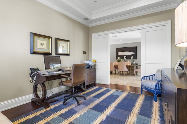 office space featuring a tray ceiling, dark hardwood / wood-style flooring, and ornamental molding