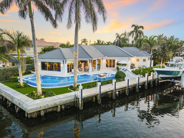 back house at dusk with a patio and a water view