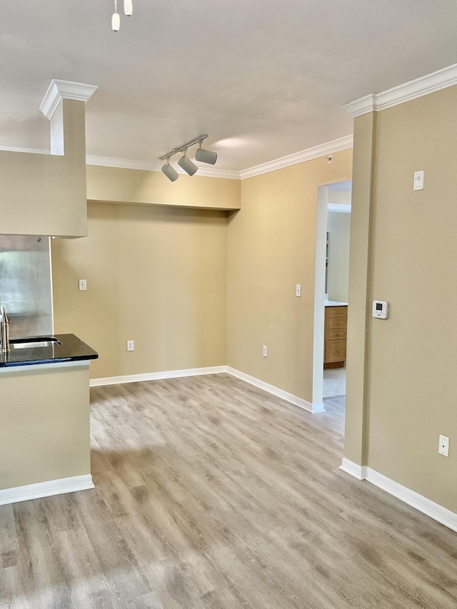 interior space with track lighting, ornamental molding, sink, and light hardwood / wood-style flooring