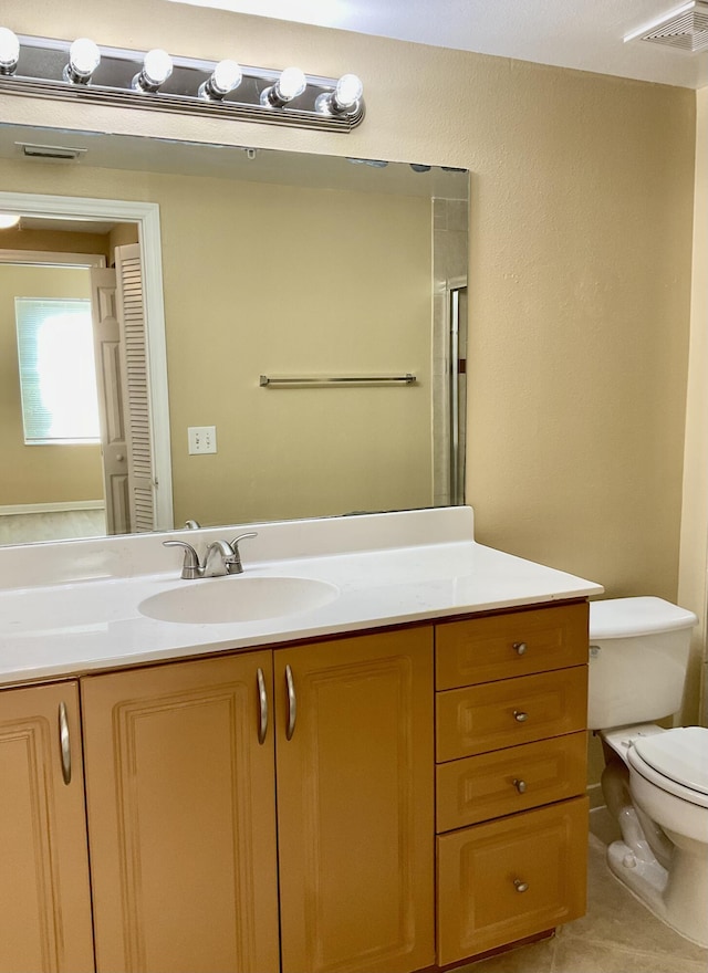 bathroom with tile patterned flooring, vanity, an enclosed shower, and toilet