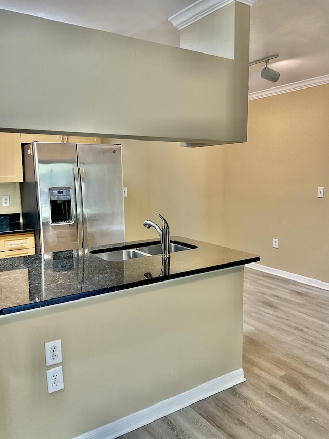 kitchen featuring sink, light hardwood / wood-style flooring, stainless steel refrigerator with ice dispenser, dark stone countertops, and crown molding