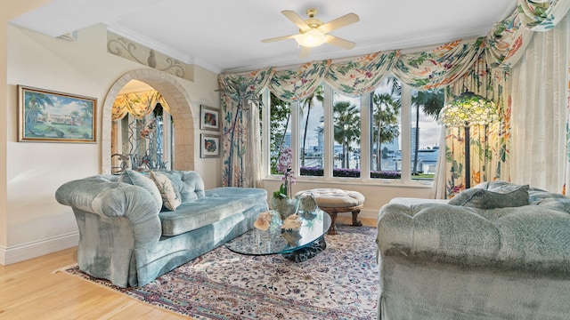 living room with crown molding, wood-type flooring, and ceiling fan