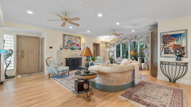 living room with light wood-style flooring, recessed lighting, a fireplace, baseboards, and crown molding