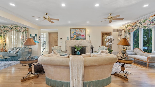 living area featuring ornamental molding, a fireplace, recessed lighting, and light wood-style floors