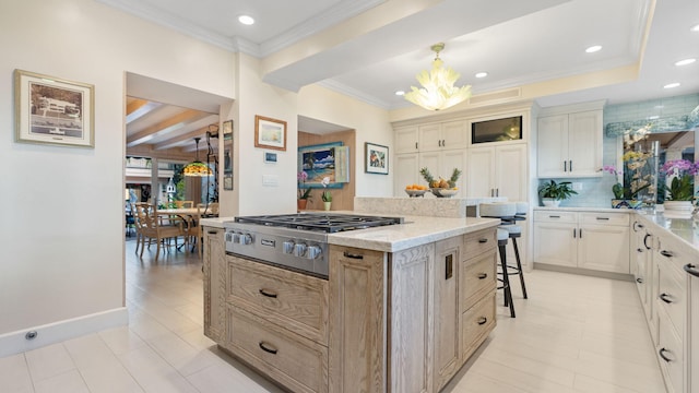 kitchen with a kitchen island, stainless steel gas stovetop, ornamental molding, backsplash, and an inviting chandelier