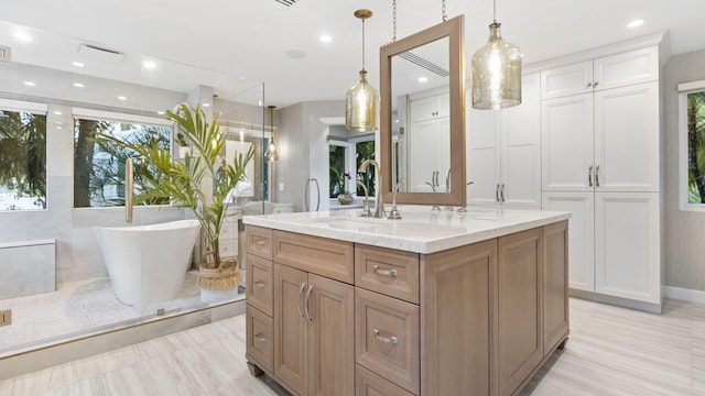 bathroom with recessed lighting, a freestanding tub, a sink, and double vanity