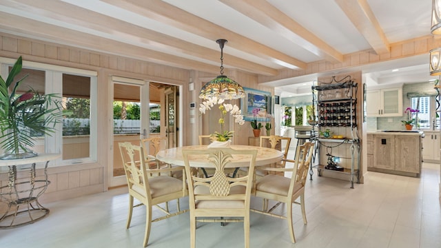 dining room with beamed ceiling and wood walls