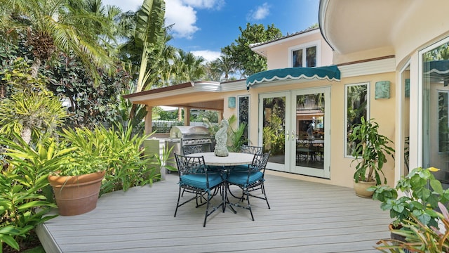 wooden deck with outdoor dining space, french doors, and grilling area