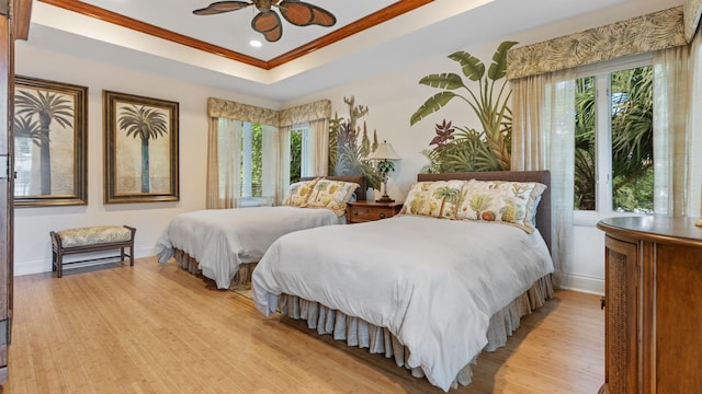 bedroom featuring recessed lighting, baseboards, light wood-style floors, a raised ceiling, and crown molding