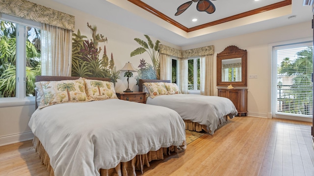 bedroom featuring crown molding, light hardwood / wood-style flooring, ceiling fan, and a raised ceiling