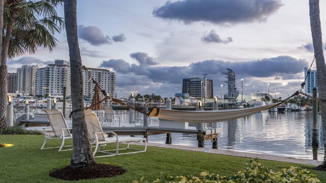 dock area featuring a view of city, a yard, and a water view