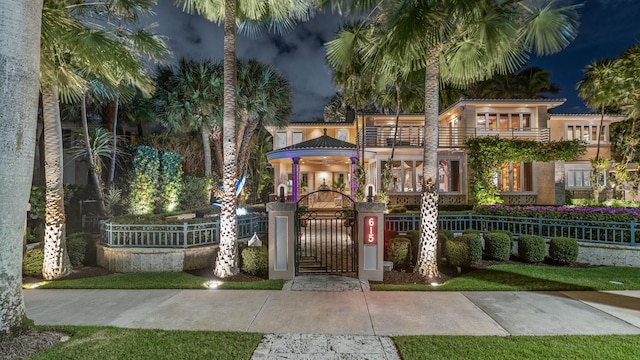 exterior space with a balcony, a fenced front yard, a gate, and stucco siding