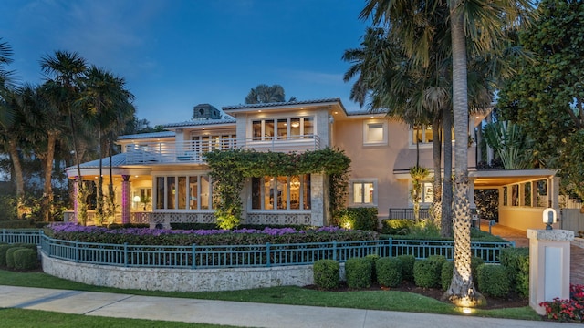 view of front of house with fence, a balcony, and stucco siding