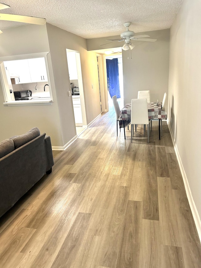 dining area with a textured ceiling, light hardwood / wood-style flooring, and ceiling fan