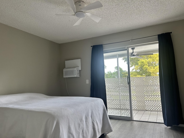 bedroom featuring access to exterior, ceiling fan, an AC wall unit, light hardwood / wood-style floors, and a textured ceiling