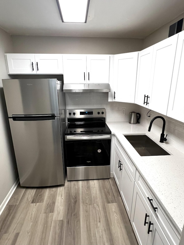 kitchen featuring sink, tasteful backsplash, light hardwood / wood-style flooring, white cabinets, and appliances with stainless steel finishes