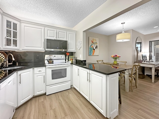 kitchen with kitchen peninsula, white appliances, white cabinetry, and sink