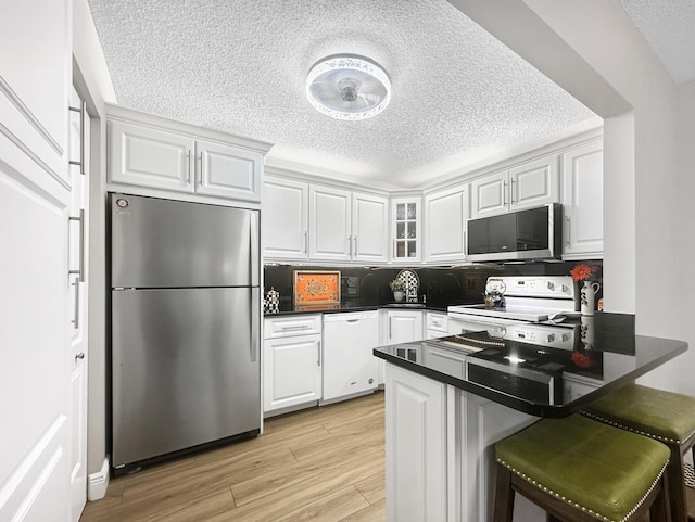 kitchen featuring kitchen peninsula, white cabinetry, stainless steel appliances, and light hardwood / wood-style flooring