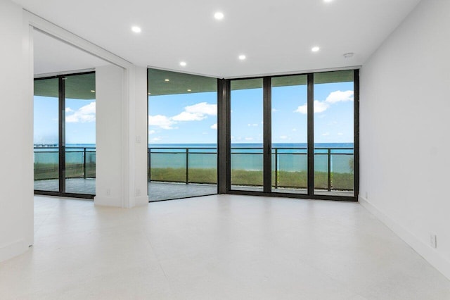 unfurnished room with a water view and expansive windows