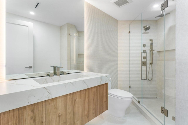 bathroom with vanity, toilet, and a shower with door