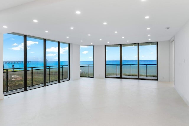 empty room featuring floor to ceiling windows, a wealth of natural light, and a water view