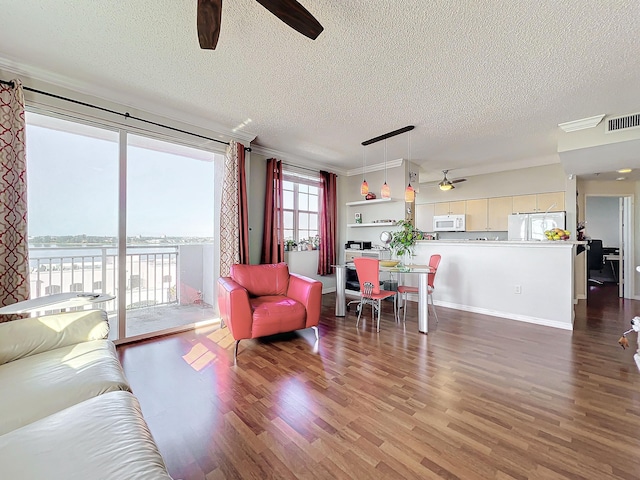 living room with hardwood / wood-style flooring, ceiling fan, a water view, and a textured ceiling