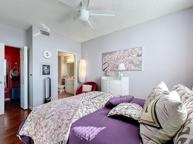 bedroom with ceiling fan, dark hardwood / wood-style floors, a textured ceiling, and ensuite bath