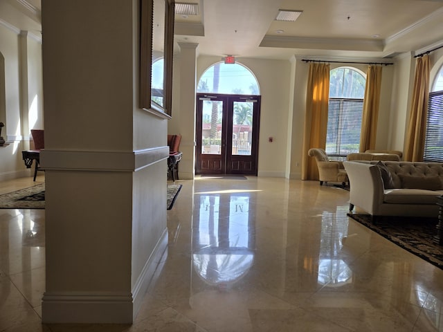 entrance foyer featuring a raised ceiling, french doors, and ornamental molding