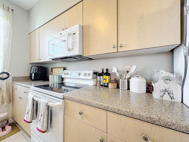 kitchen featuring light brown cabinetry, light tile patterned flooring, and white appliances