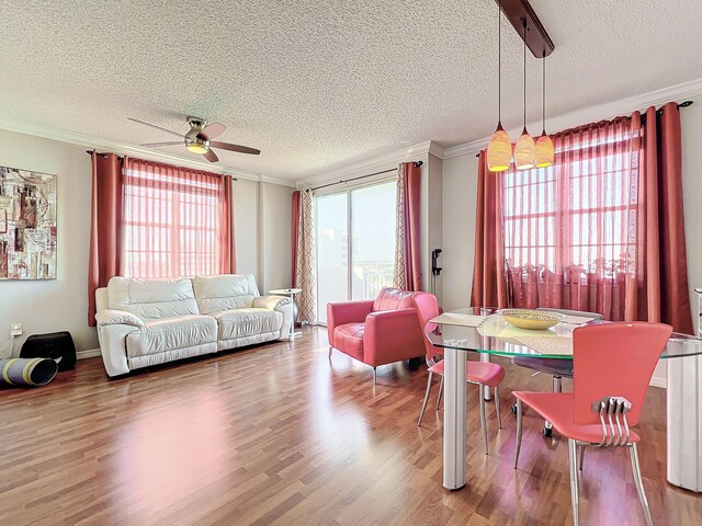 living room featuring hardwood / wood-style floors, ceiling fan, crown molding, and a textured ceiling