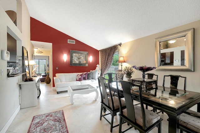 tiled dining area featuring high vaulted ceiling and a textured ceiling