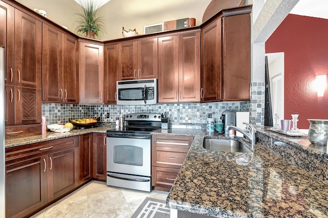 kitchen featuring appliances with stainless steel finishes, tasteful backsplash, sink, light tile patterned floors, and dark stone countertops