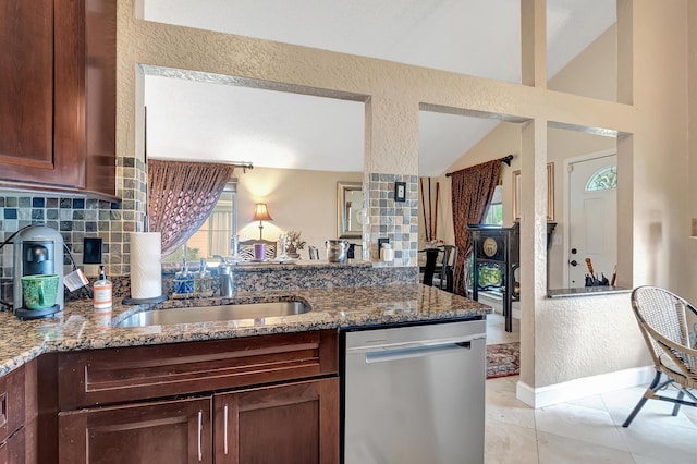 kitchen featuring sink, stainless steel dishwasher, dark stone countertops, lofted ceiling, and decorative backsplash